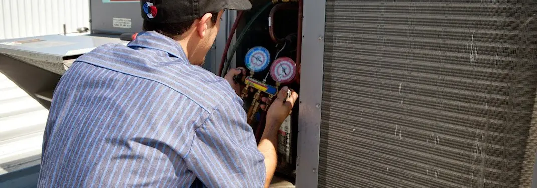 HVAC technician servicing a condenser unit in Quincy